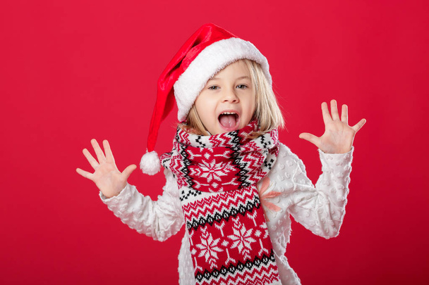 bambina in cappello di Babbo Natale e sciarpa su sfondo rosso
 - Foto, immagini