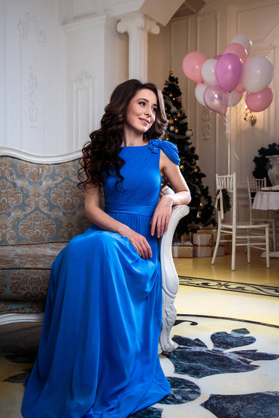 beautiful young woman in a blue evening dress with air balloons over christmas background - Foto, Imagem