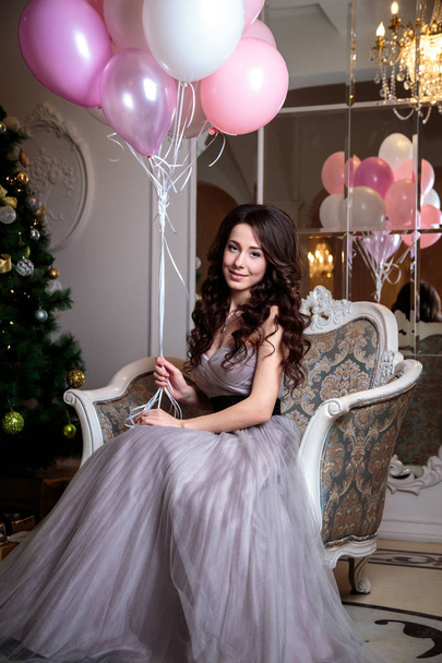 beautiful young woman in luxury evening dress with air balloons over christmas background - Fotó, kép