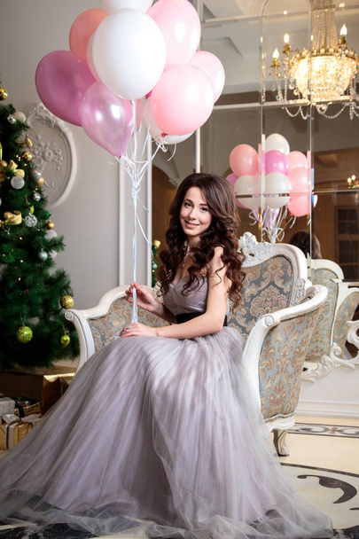 beautiful young woman in luxury evening dress with air balloons over christmas background - Photo, Image