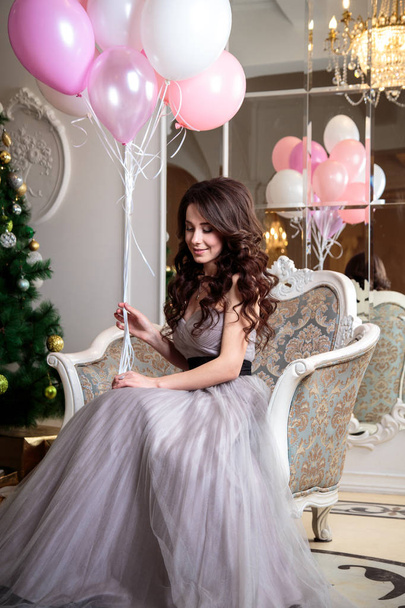beautiful young woman in luxury evening dress with air balloons over christmas background - Foto, afbeelding