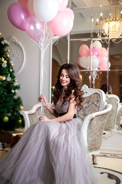 beautiful young woman in luxury evening dress with air balloons over christmas background - Photo, image