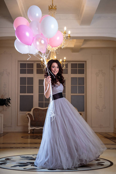beautiful young woman in luxury evening dress with air balloons in interior - Фото, изображение