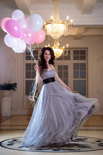 beautiful young woman in luxury evening dress with air balloons in interior - Foto, imagen