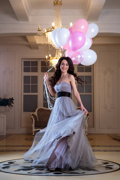 beautiful young woman in luxury evening dress with air balloons in interior - Foto, imagen