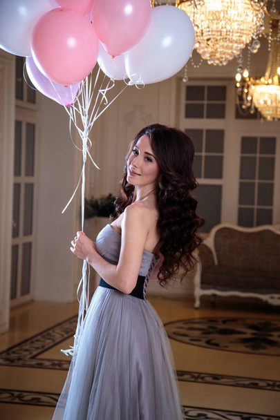 beautiful young woman in luxury evening dress with air balloons in interior - Photo, image