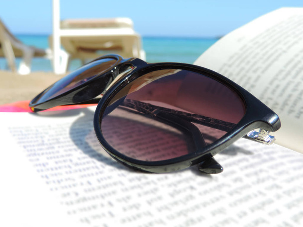 Óculos de sol e livro na praia
 - Foto, Imagem