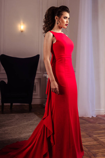 young lady in a gorgeous red evening dress in interior - Фото, изображение