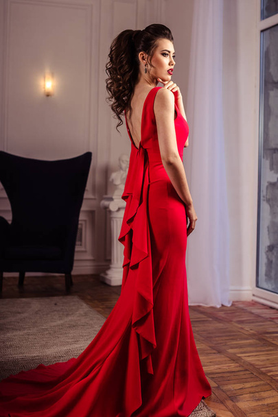 young lady in a gorgeous red evening dress in interior - 写真・画像