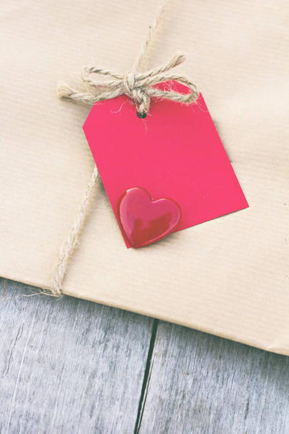 Подарунок в крафт-папері з червоною карткою та серцем
 - Фото, зображення