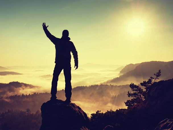 Mies seisoo korkealla kalliolla. Retkeilijä kiipesi ylös kivinen huippu ja nauttia näkymä
 - Valokuva, kuva