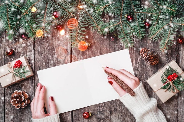 Női kézzel írt levélben Santa fa háttér, karácsonyi ajándékok, fenyő ágak, kéreg textúra, fenyőtobozok, piros díszek. Karácsonyt és boldog új évet kártya. Lapos feküdt, top view - Fotó, kép