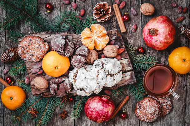 クリスマス カード。クッキー チョコレート、紅茶、ザクロ、ミカン、ナッツ、カカオ豆、木製の背景上のモミの枝。テーマはクリスマスと新年あけましておめでとうございます。トップ ビューの選択と集中 - 写真・画像