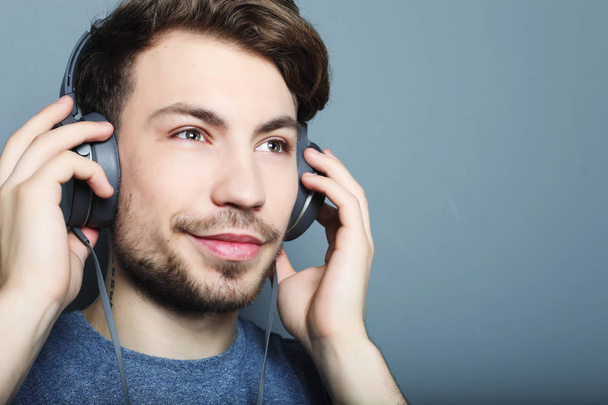 Handsome young man wearing headphones and listening to music. - 写真・画像