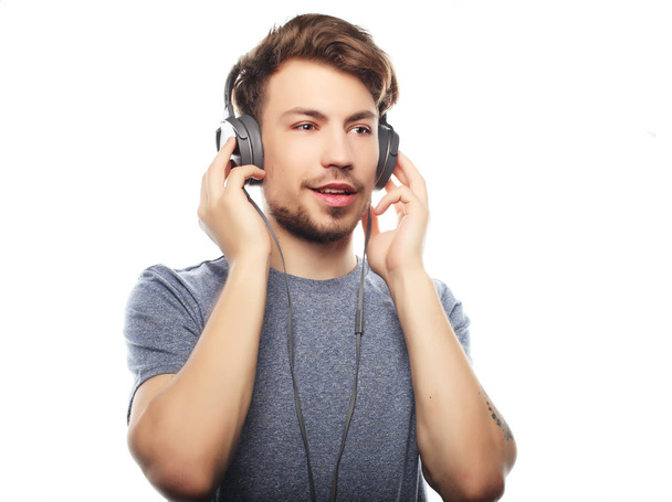 Handsome young man wearing headphones and smiling while standing - Foto, immagini