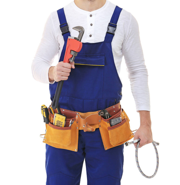 Plumber in blue uniform holding tools on white background - Фото, изображение