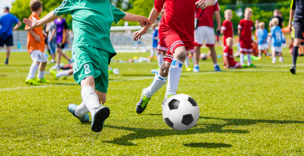 スポーツ フィールドでサッカー サッカー ゲームを遊んでいる子供たち。男の子は、緑の芝生でサッカーの試合を再生します。青年サッカーのトーナメント チーム大会 - 写真・画像