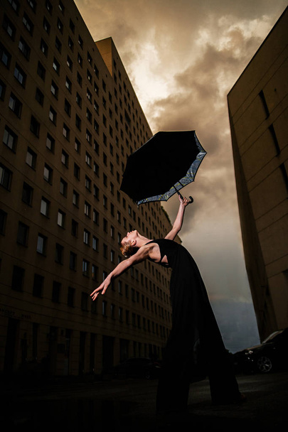 Ballerine avec parasol sur la rue de la ville sur fond ciel et bui
 - Photo, image