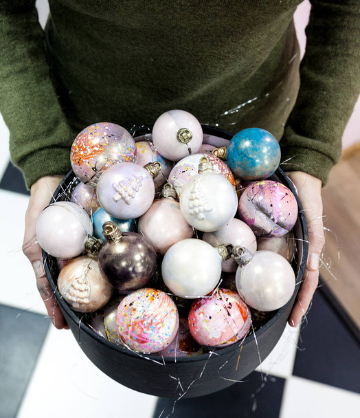 Mani che tengono le palline di cioccolato dipinte a mano di Natale in una scatola regalo nera
.  - Foto, immagini