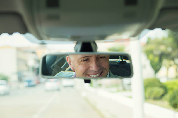 Closeup portrait, happy young man driver looking at rear view mi - Фото, изображение