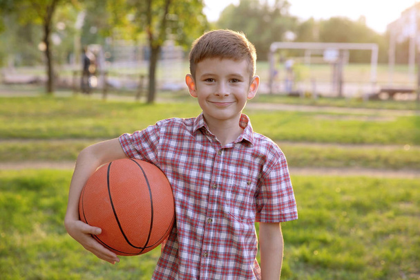 Cute boy with basketball ball on street - Фото, изображение