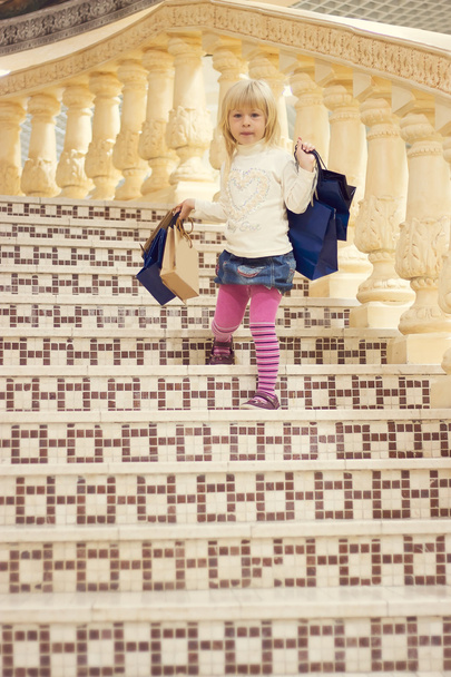 girl 3 years old comes down stairs with shopping - Fotoğraf, Görsel