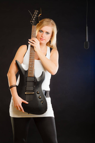 Blonde woman holding electric guitar, black background - Foto, Imagem
