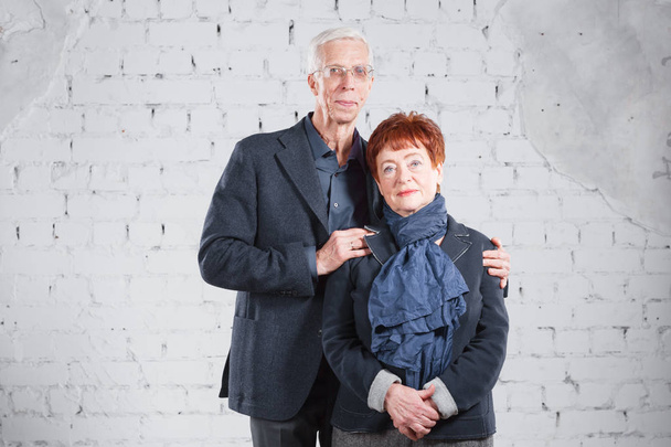 Felice sorridente vecchia coppia in piedi coccole insieme isolato su sfondo di mattoni bianchi. copia spazio
. - Foto, immagini