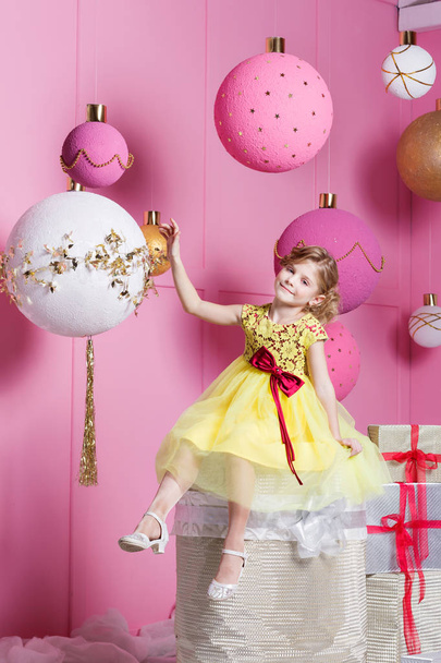 Güzel kız çocuk sarı bir elbise içinde 6 yaşında. Bebek Rose kuvars odada tatil dekore edilmiştir.. - Fotoğraf, Görsel