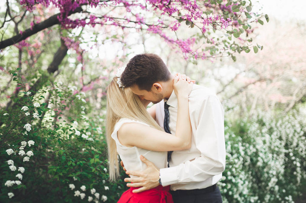 stilvolle schöne glückliche Hochzeitspaar küsst und umarmt im botanischen Garten - Foto, Bild