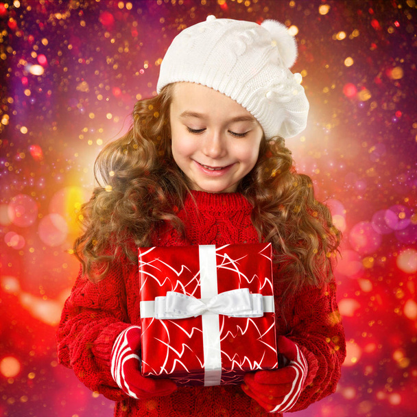 Happy little girl with Christmas gift over lights background - Foto, immagini