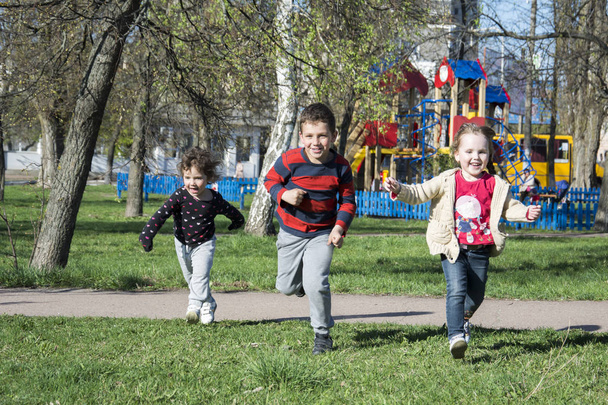 Primavera begaayut crianças na grama perto do parque infantil
. - Foto, Imagem