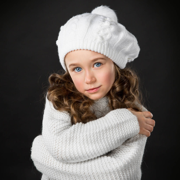 Fashion little girl dressed in winter clothing, isolated on dark background - Fotó, kép