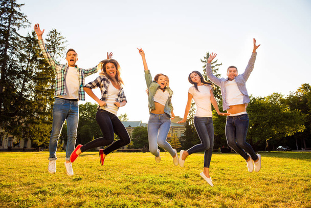 Five joyful boyfriends and girlfriends jumping and having fun on - Фото, зображення