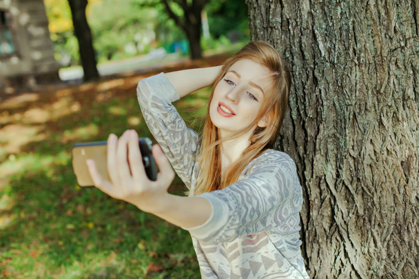 Gyönyörű lány, kék szemek teszi selfie szabadban - Fotó, kép
