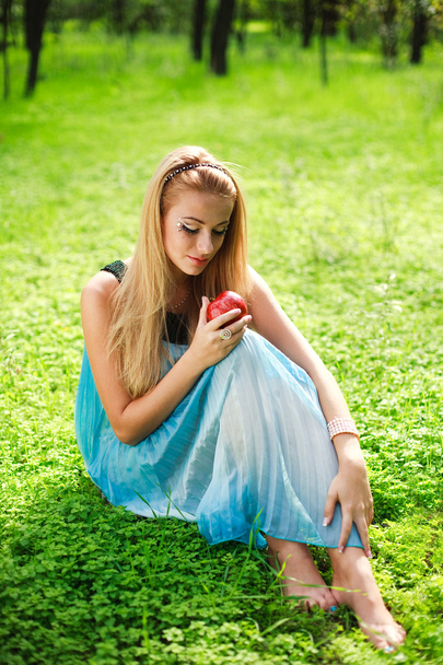 Portrait of beautiful girl in green park with red apple - Фото, зображення
