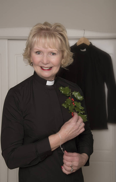 Mulher religiosa de preto segurando um raminho de Holly
 - Foto, Imagem