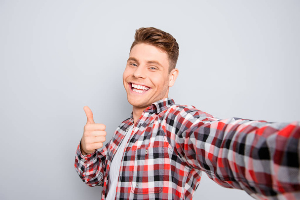 Handsome cheerful young man making selfie and showing thumb up - Foto, immagini