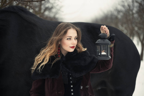 meisje in donkere kleding met een zwart paard - Foto, afbeelding
