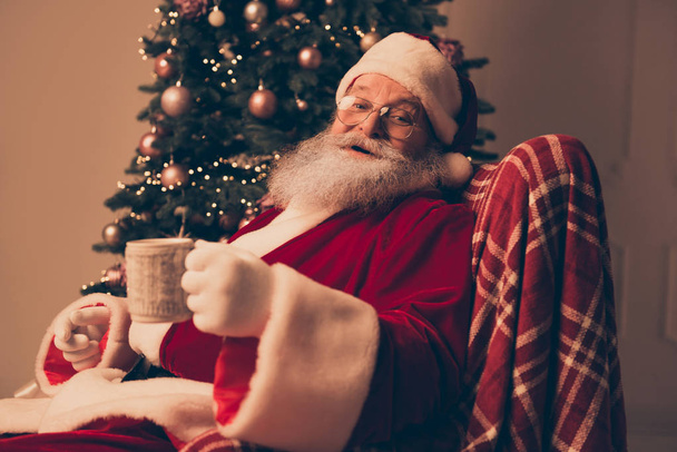 Portrait of happy Santa Claus resting at home and drinking tea - Fotó, kép