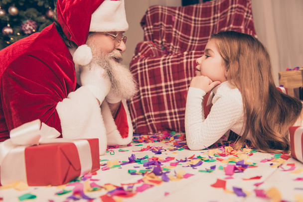 Happy Santa Claus lying on floor and talking with cute little gi - Foto, afbeelding
