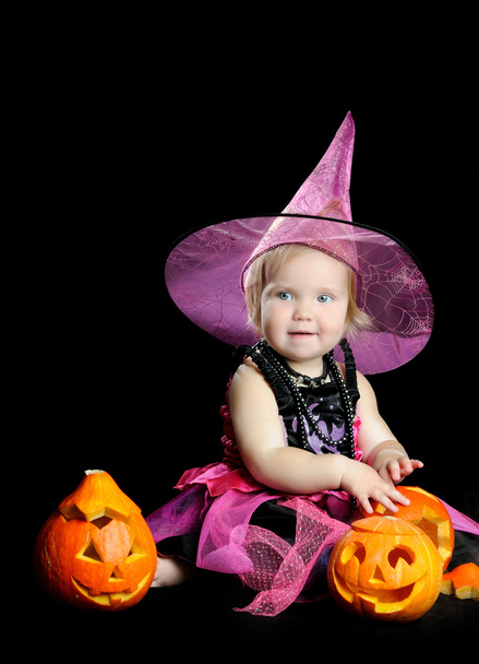 Halloween baby witch with a carved pumpkin over black background - Zdjęcie, obraz