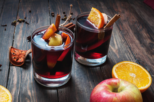 Hot mulled wine with spices, apple and orange on wood background - Photo, Image