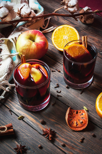 Hot mulled wine with spices, apple and orange on wood background - Фото, зображення