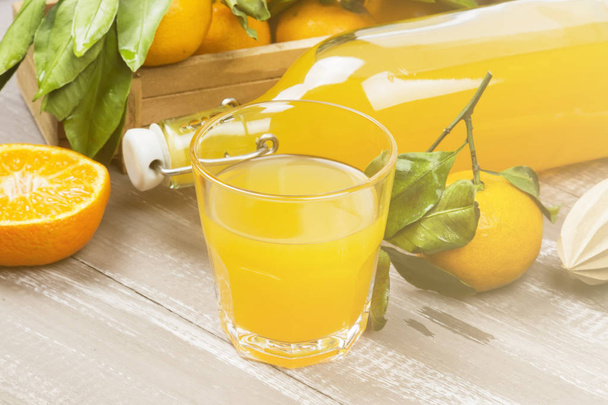 Tangerine juice in glass and fresh fruit on a wooden background. - Foto, imagen