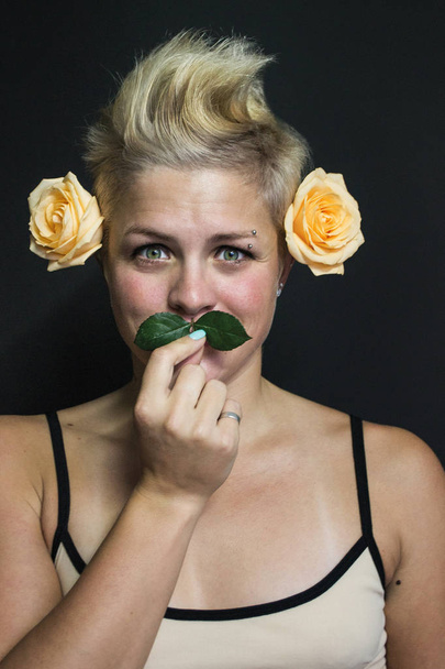 смішний портрет блондинки з короткими волоссям дівчини з трояндами у волоссі та пелюстках як вуса
 - Фото, зображення