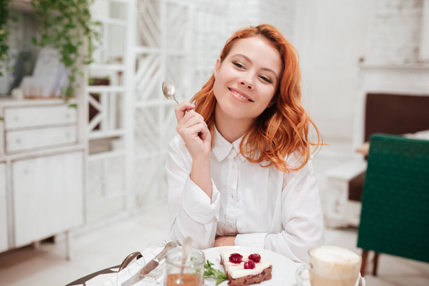 Young redhead pretty woman eating cake in cafe - Zdjęcie, obraz