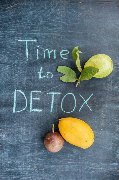 TIME TO DETOX chalk inscription on the wooden table fruits: mango, passion fruit and guava. Health Concept - Foto, Bild