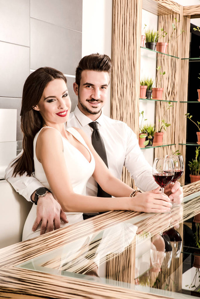 A romantic couple with a glass of wine in the dining room - Photo, image
