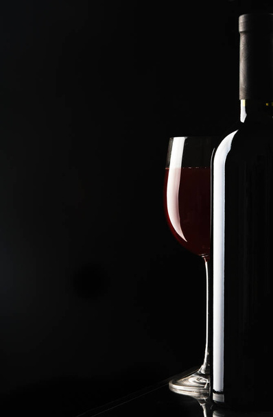 Glass of wine and a bottle on black background - Foto, Imagem